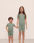 Model is wearing Kids TENCEL™ Modal Unisex Short PJ Set in Eucalyptus/Ivory