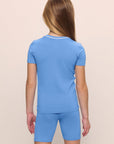 Model is wearing the Kids TENCEL™ Modal Unisex Short PJ Set in cornflower blue/white