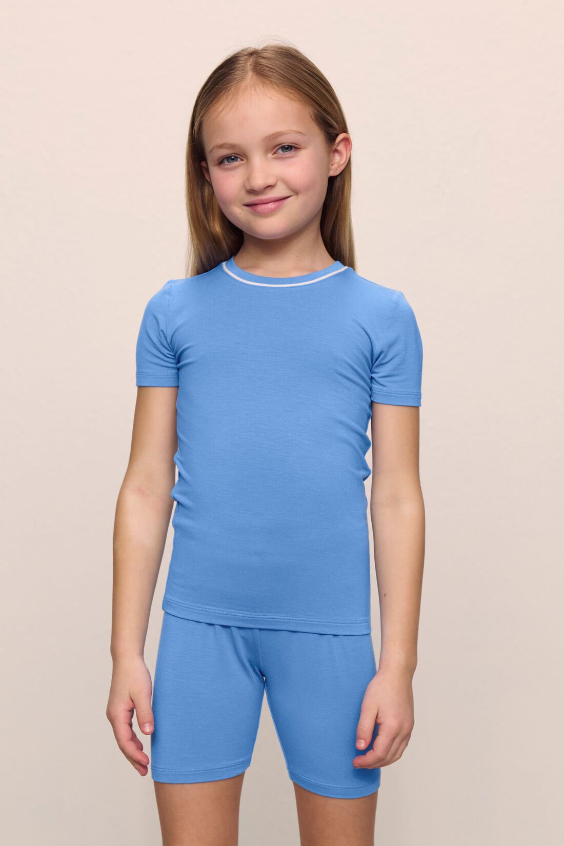 Model is wearing the Kids TENCEL™ Modal Unisex Short PJ Set in cornflower blue/white
