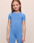 Model is wearing the Kids TENCEL™ Modal Unisex Short PJ Set in cornflower blue/white