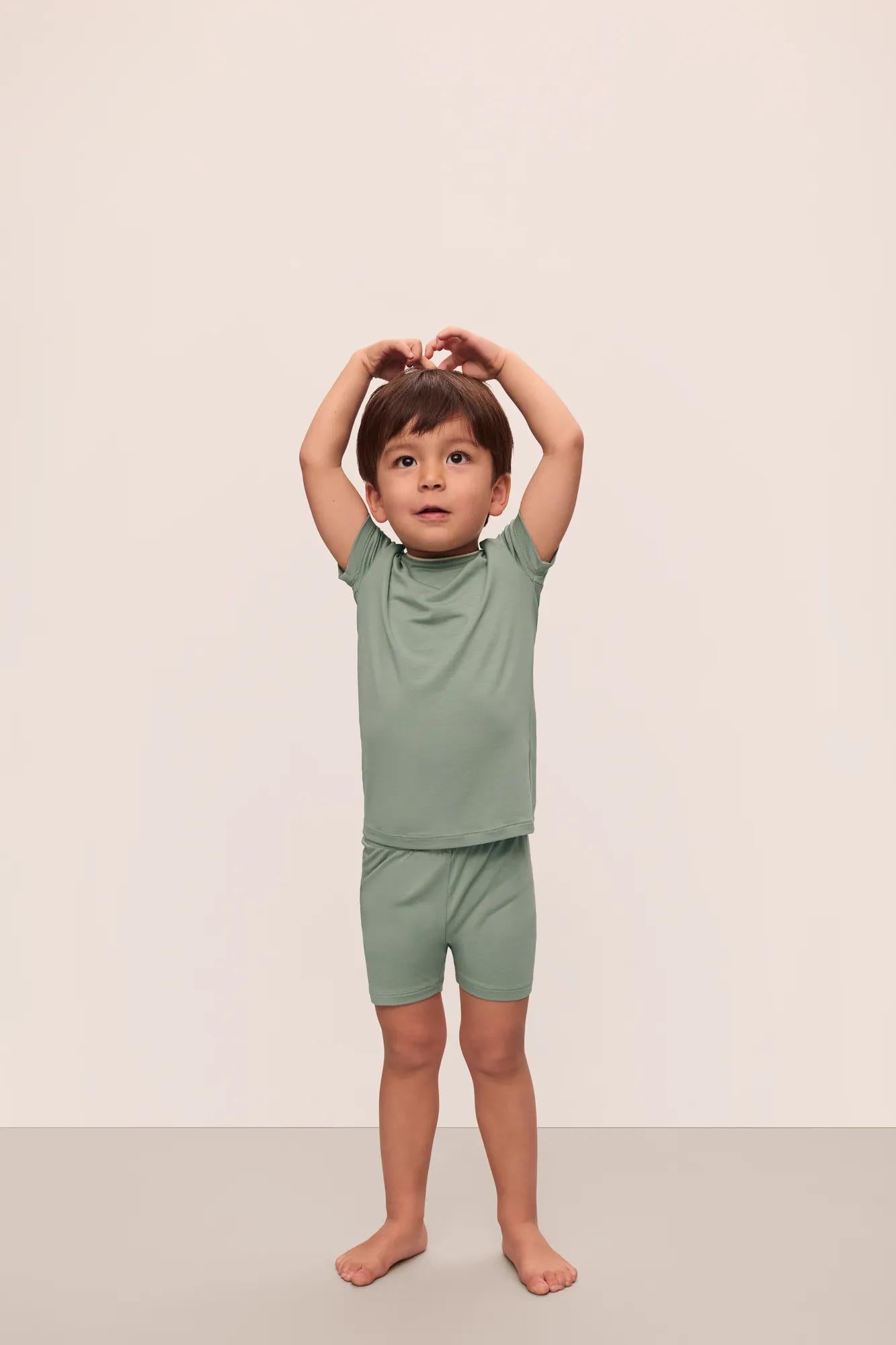 Model is wearing Kids TENCEL™ Modal Unisex Short PJ Set in Eucalyptus/Ivory