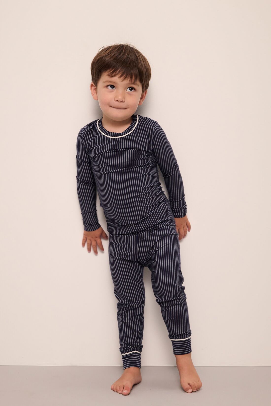 Model wears Kids TENCEL™ Modal Unisex Long PJ Set in Duo Stripe True Navy/Ivory.