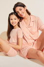 Model wears Kids TENCEL™ Modal Unisex Short PJ Set in Peach Parfait/Ivory.