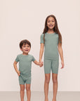 Models are wearing Kids TENCEL™ Modal Unisex Short PJ Set in Eucalyptus/Ivory