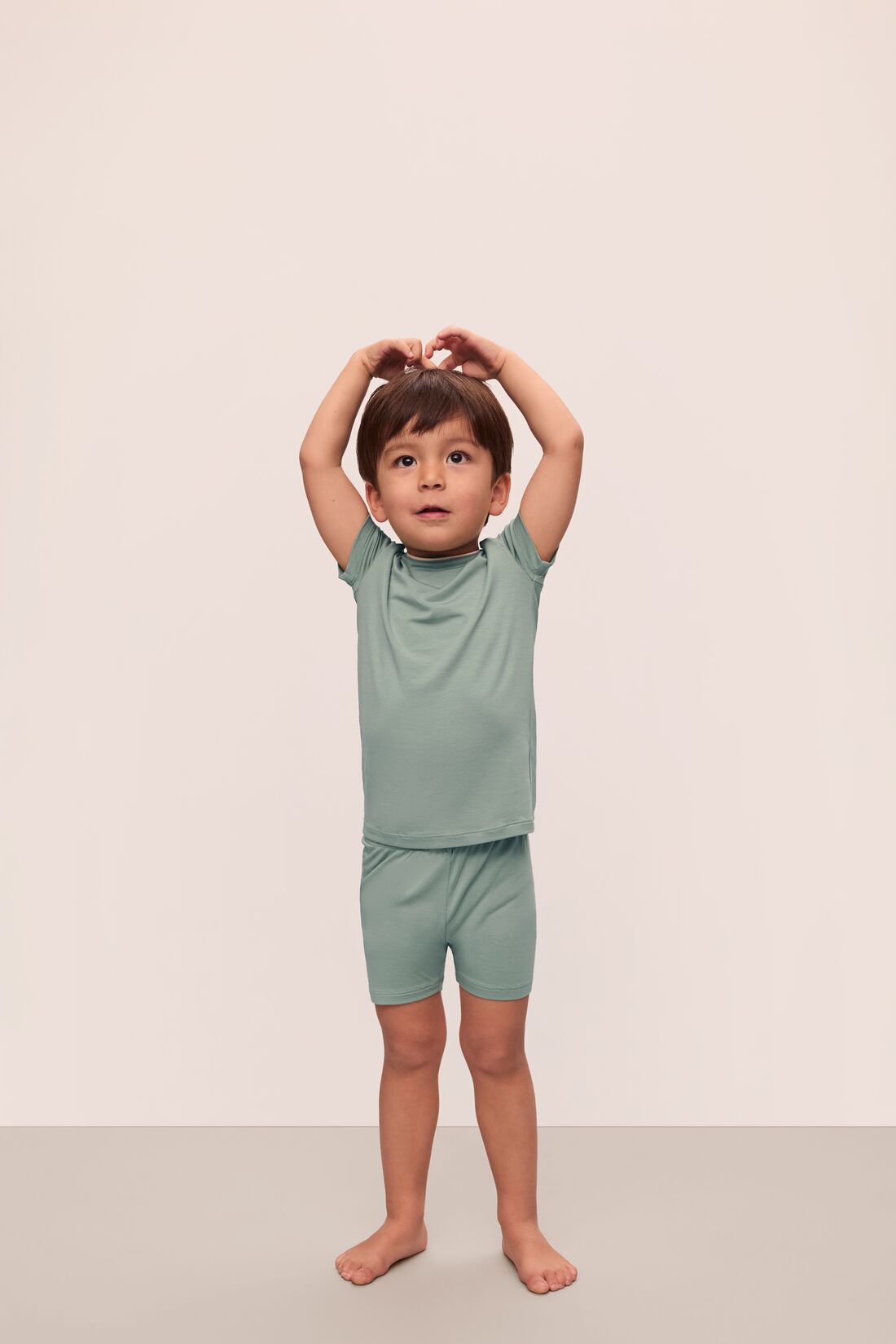 Model is wearing Kids TENCEL™ Modal Unisex Short PJ Set in Eucalyptus/Ivory