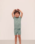 Model is wearing Kids TENCEL™ Modal Unisex Short PJ Set in Eucalyptus/Ivory