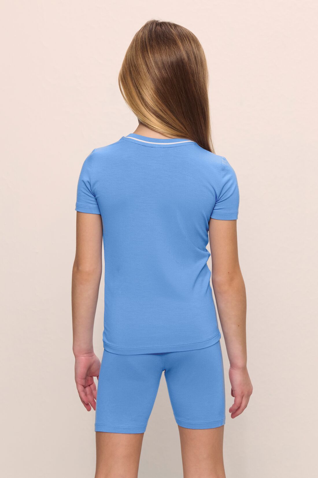 Model is wearing the Kids TENCEL™ Modal Unisex Short PJ Set in cornflower blue/white