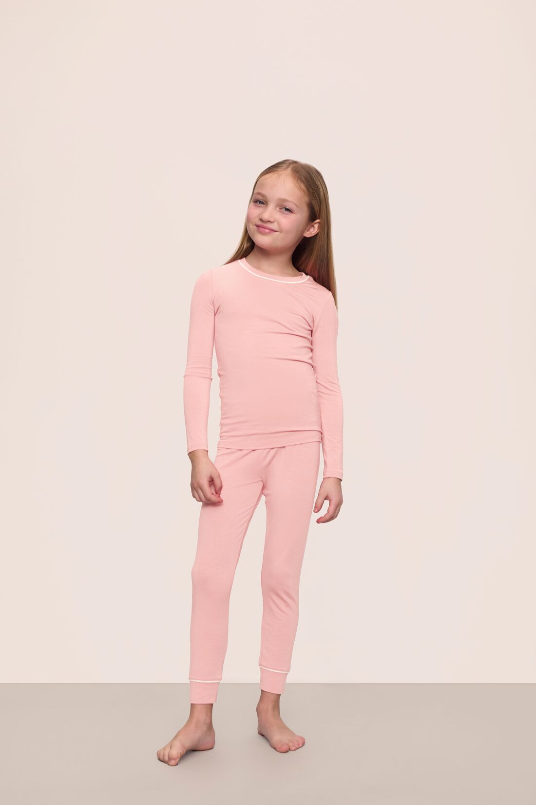 Model is wearing Kids TENCEL™ Modal Unisex Long PJ Set in Silver Pink/Ivory