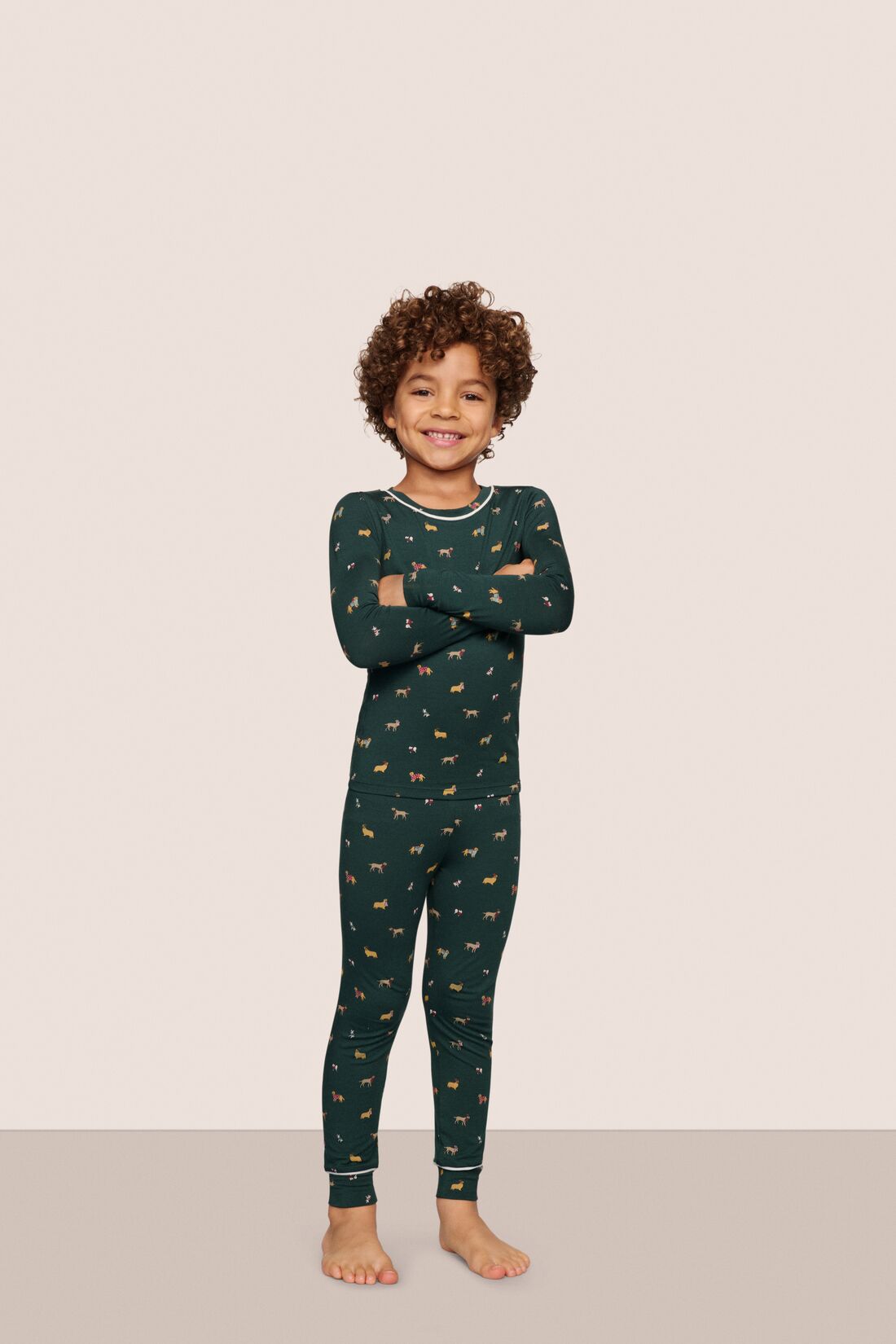 Model is wearing Kids Printed TENCEL™ Modal Unisex Long PJ Set  in Holiday Dogs Pine/Ivory