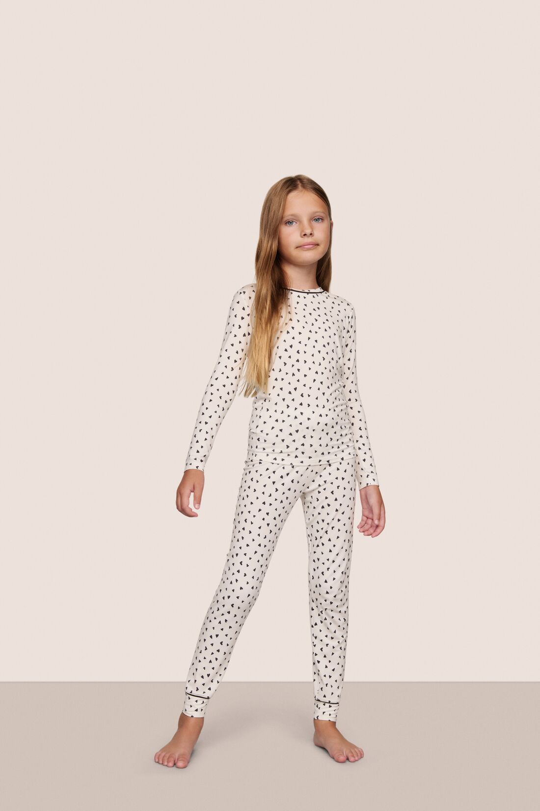 Model is wearing Kids Printed TENCEL™ Modal Unisex Long PJ Set  in Heart To Heart Black/Blk