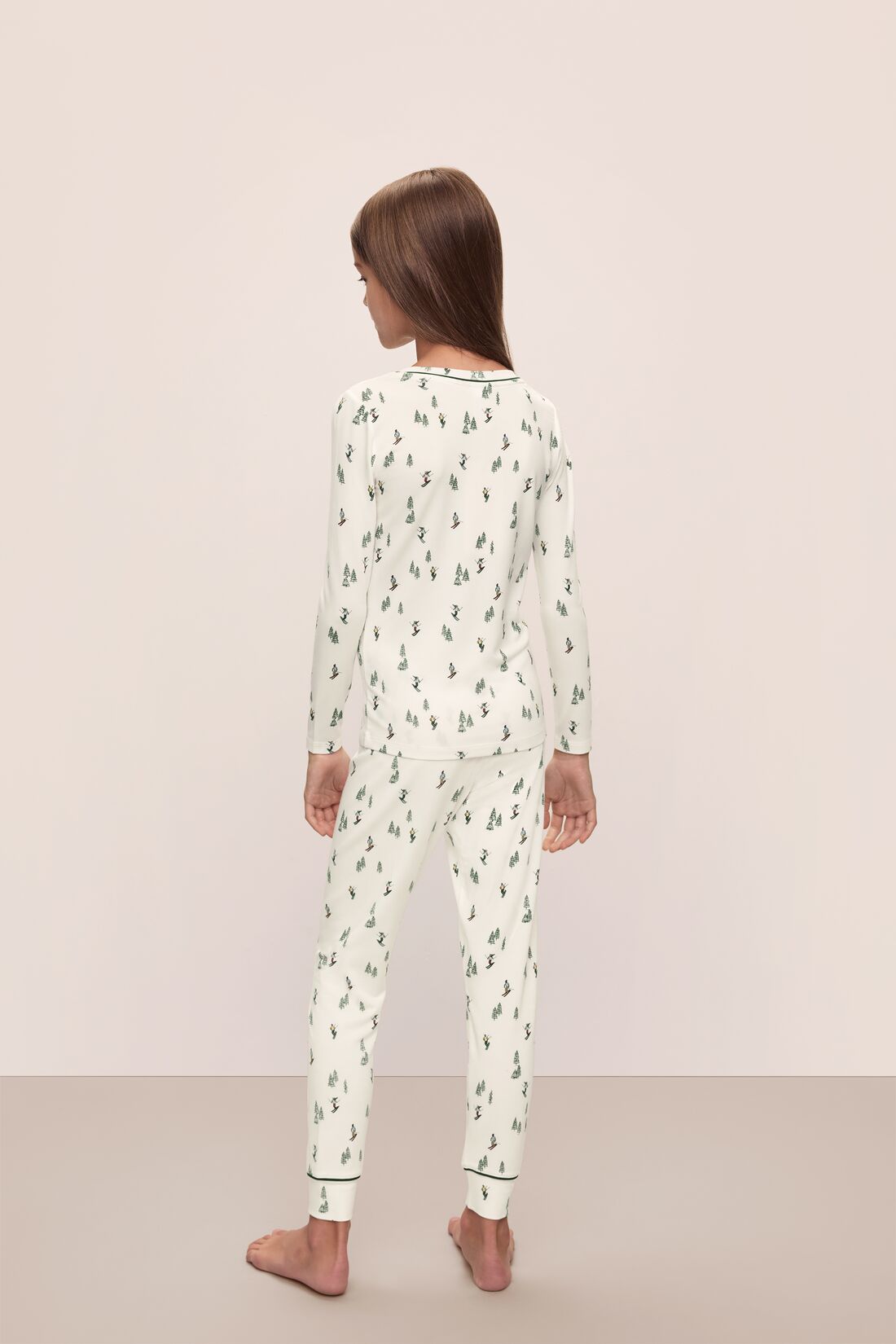 Model wears Kids Printed TENCEL™ Modal Unisex Long PJ Set in Alpine Skier Ivory/Forest Green.