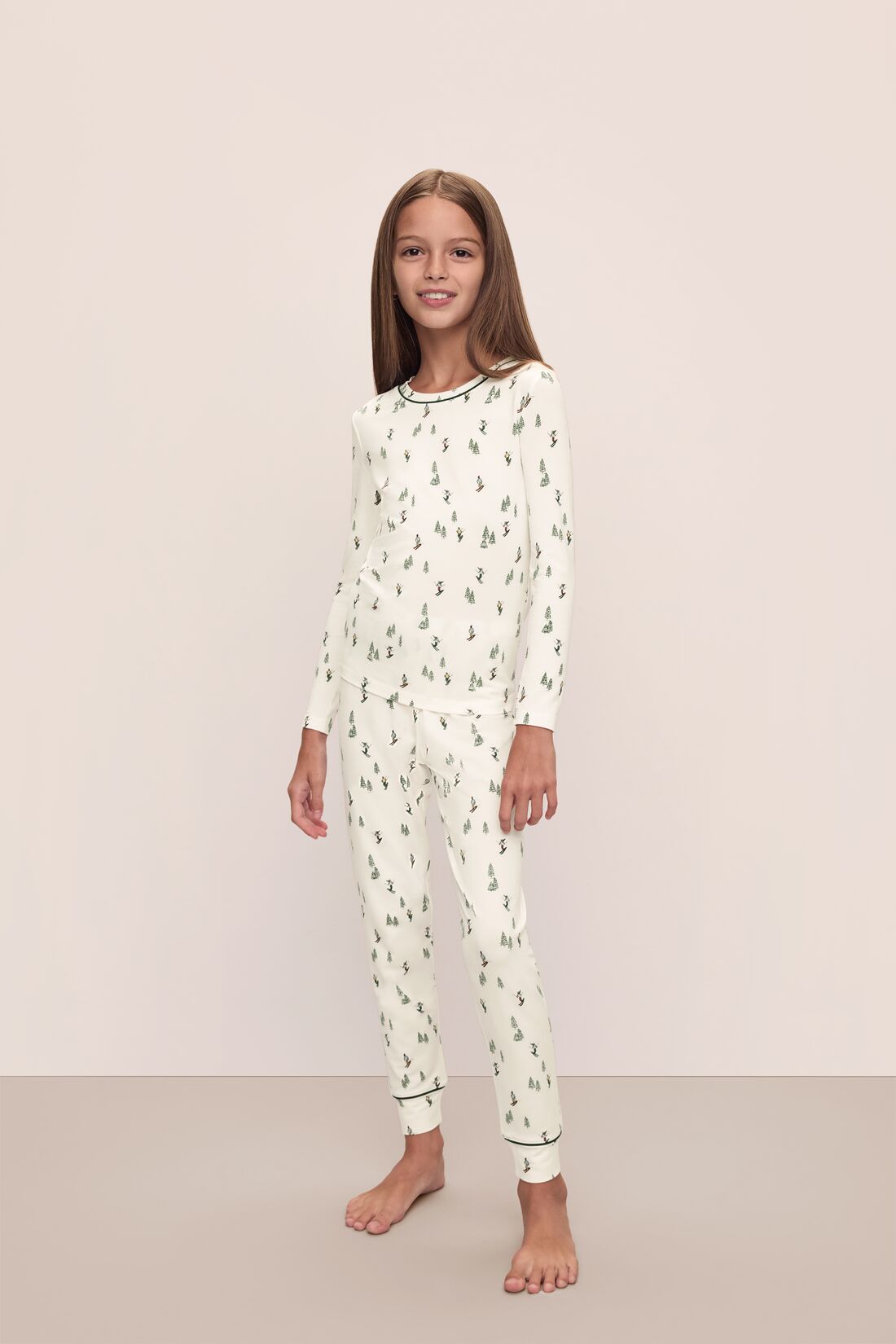 Model wears Kids Printed TENCEL™ Modal Unisex Long PJ Set in Alpine Skier Ivory/Forest Green.