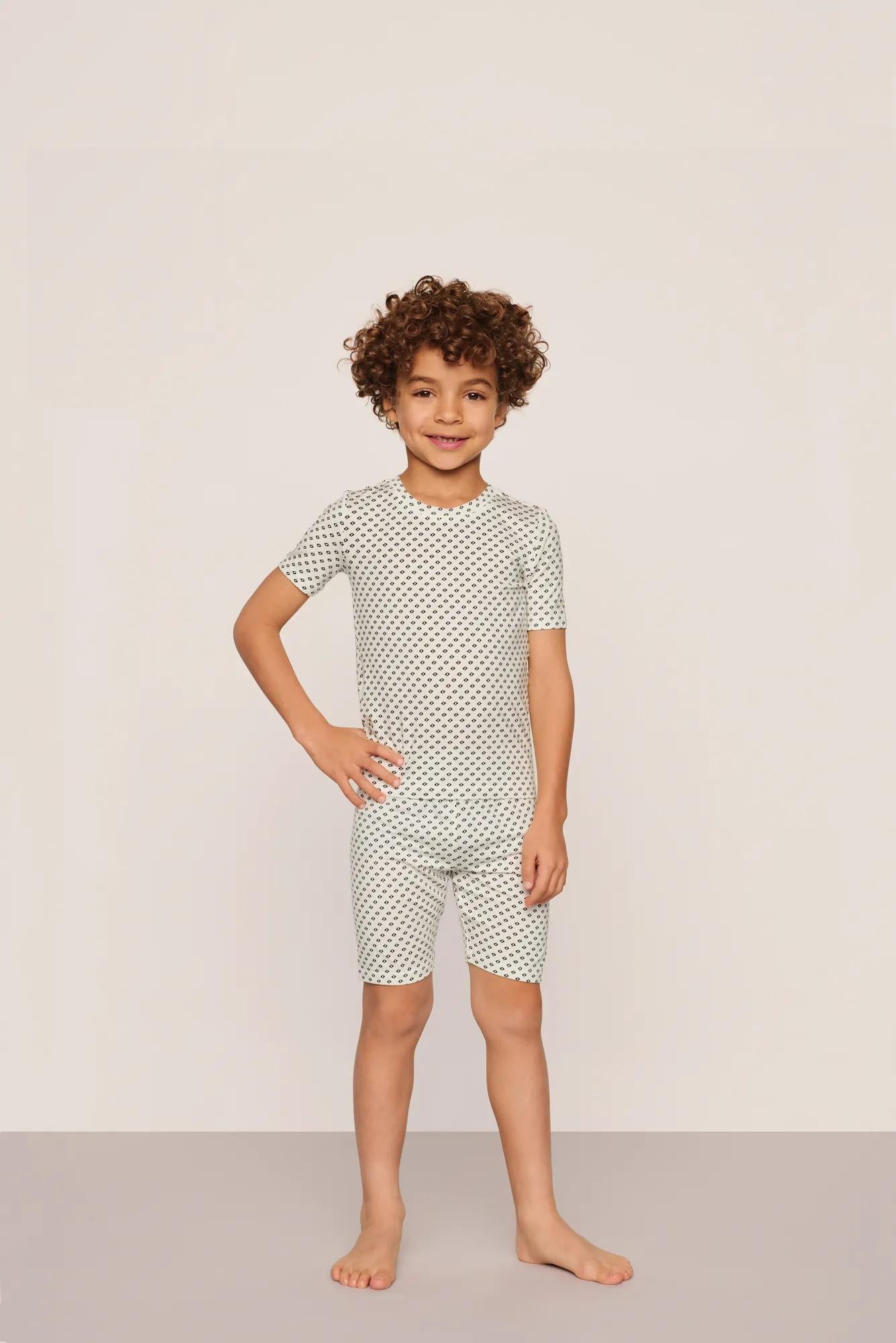 Model is wearing Kids Printed TENCEL™ Modal Unisex Short PJ Set in Tide Dot Ivory/Ivory