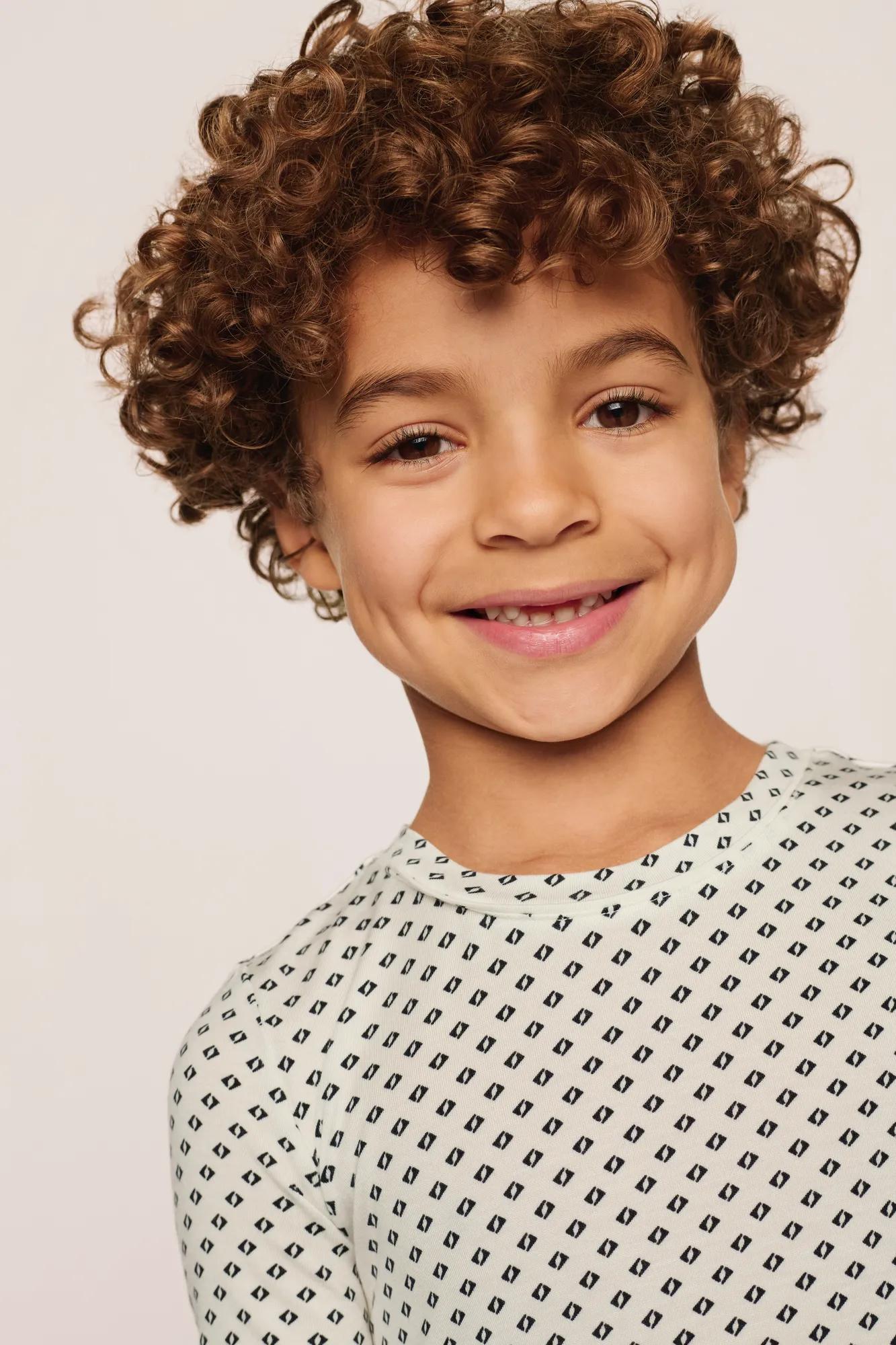 Model is wearing Kids Printed TENCEL™ Modal Unisex Short PJ Set in Tide Dot Ivory/Ivory