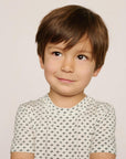 Model is wearing Kids Printed TENCEL™ Modal Unisex Short PJ Set in Tide Dot Ivory/Ivory
