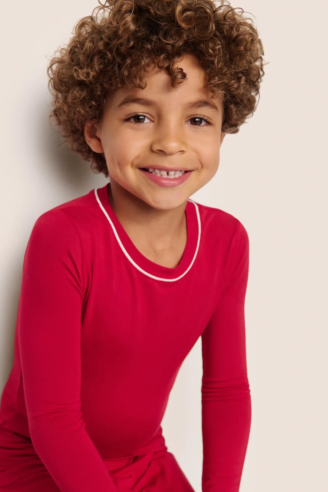 Model is wearing Kids TENCEL™ Modal Unisex Long PJ Set  in Holly Red/Ivory