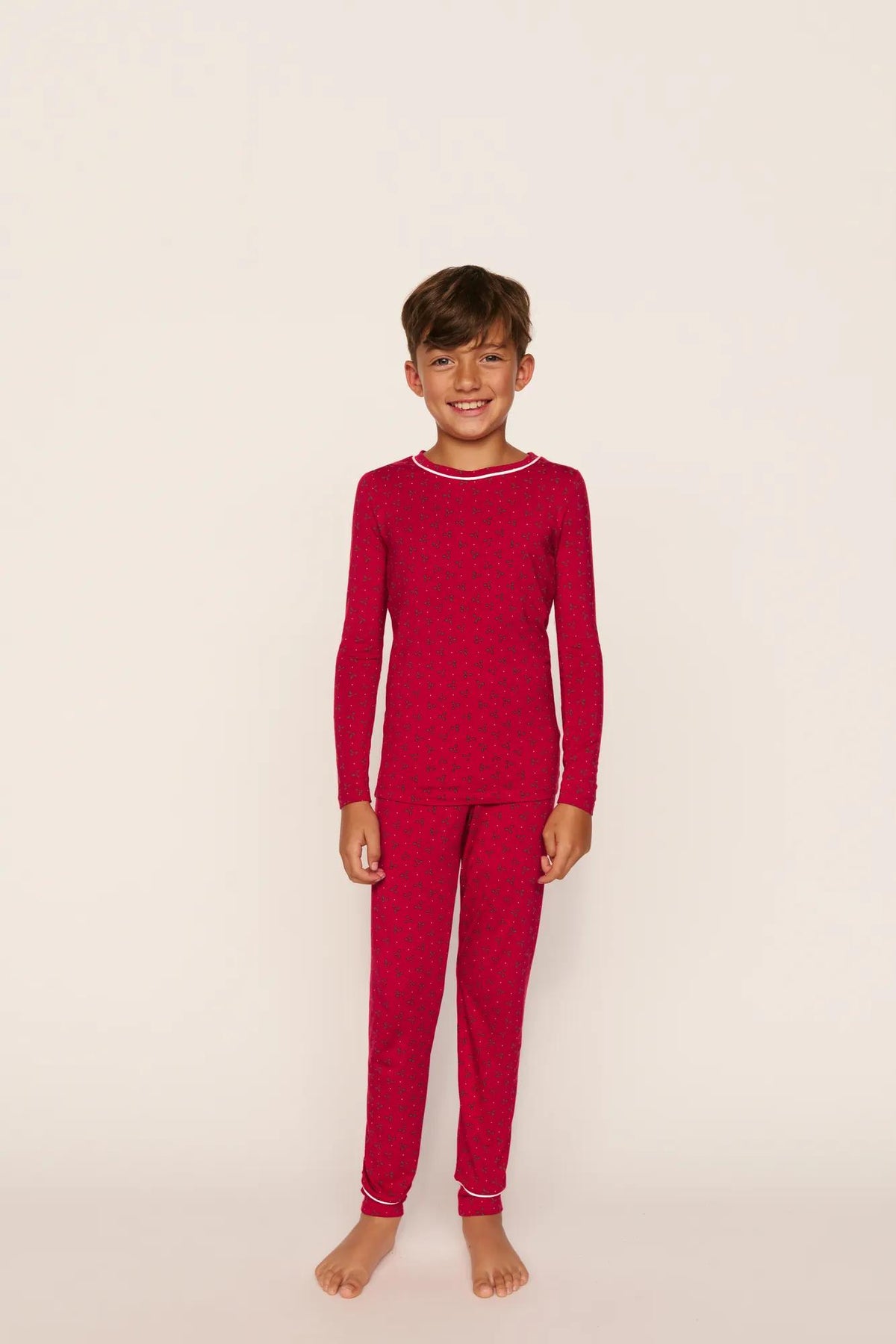 Model is wearing Kids Printed TENCEL™ Modal Unisex Long PJ Set in Hollyberry Holly Red/Ivory