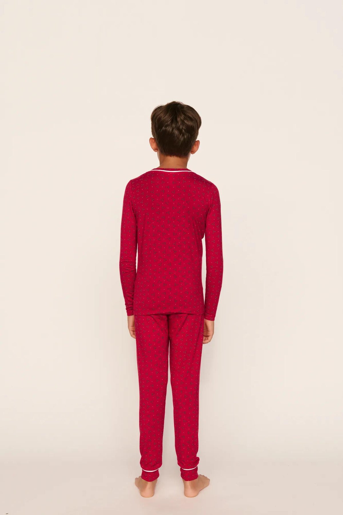 Model is wearing Kids Printed TENCEL™ Modal Unisex Long PJ Set in Hollyberry Holly Red/Ivory
