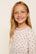 Model is wearing Kids Printed TENCEL™ Modal Unisex Long PJ Set in Mini Bow Ivory/Holly Red