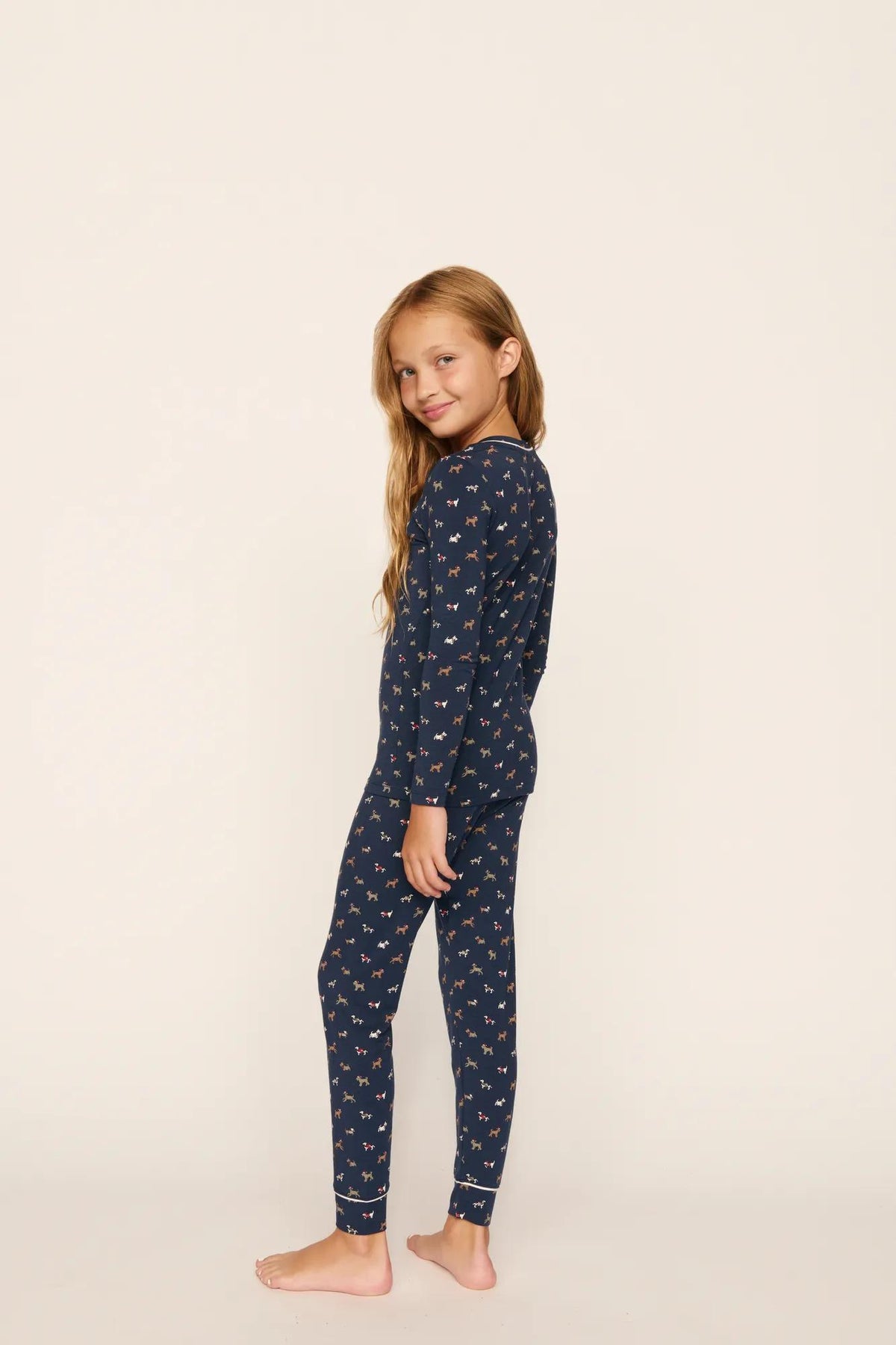 Model is wearing Kids Printed TENCEL™ Modal Unisex Long PJ Set in Santa Paws Navy/Ivory