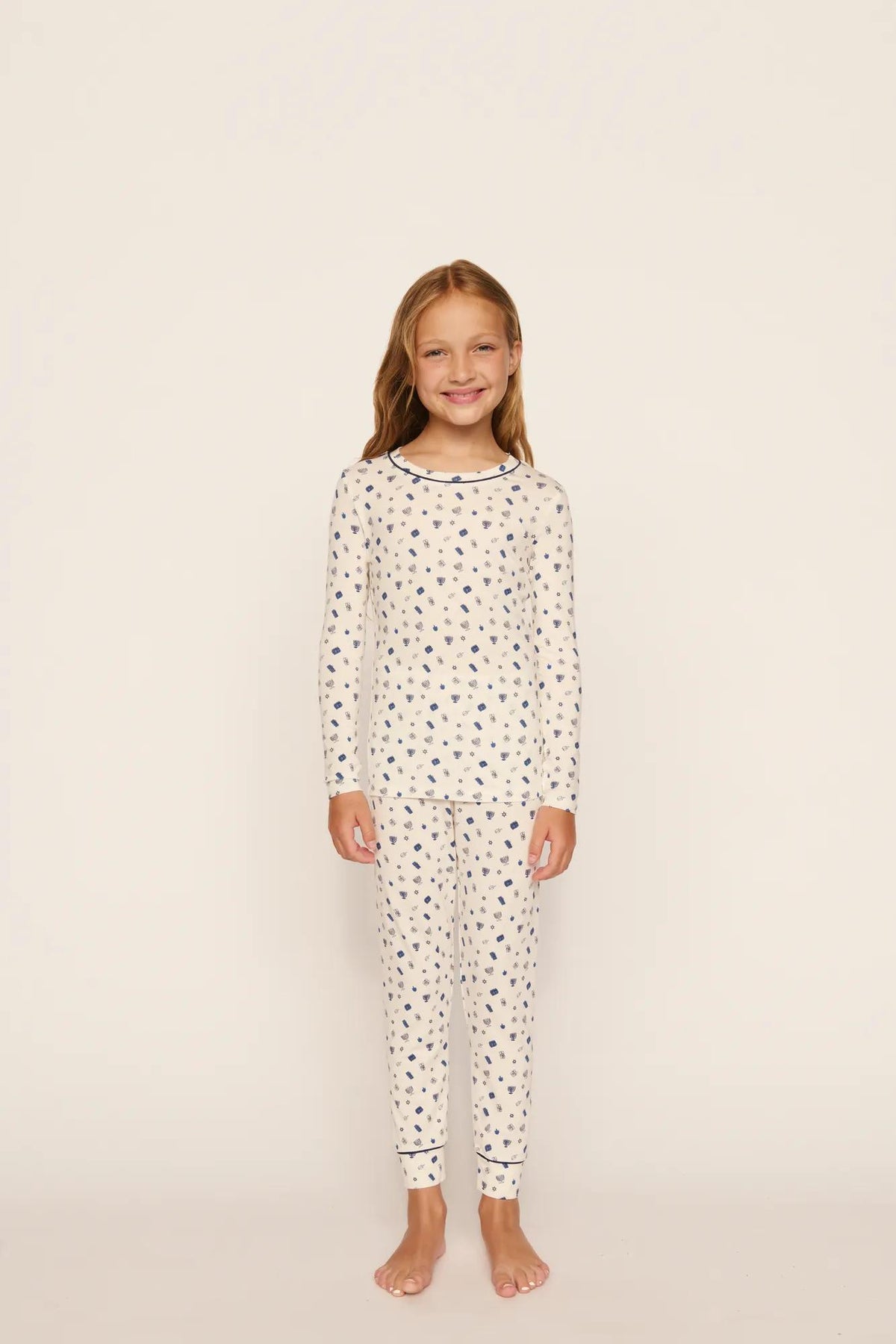 Model is wearing Kids Printed TENCEL™ Modal Unisex Long PJ Set in Twinkling Menorah Ivory/Navy