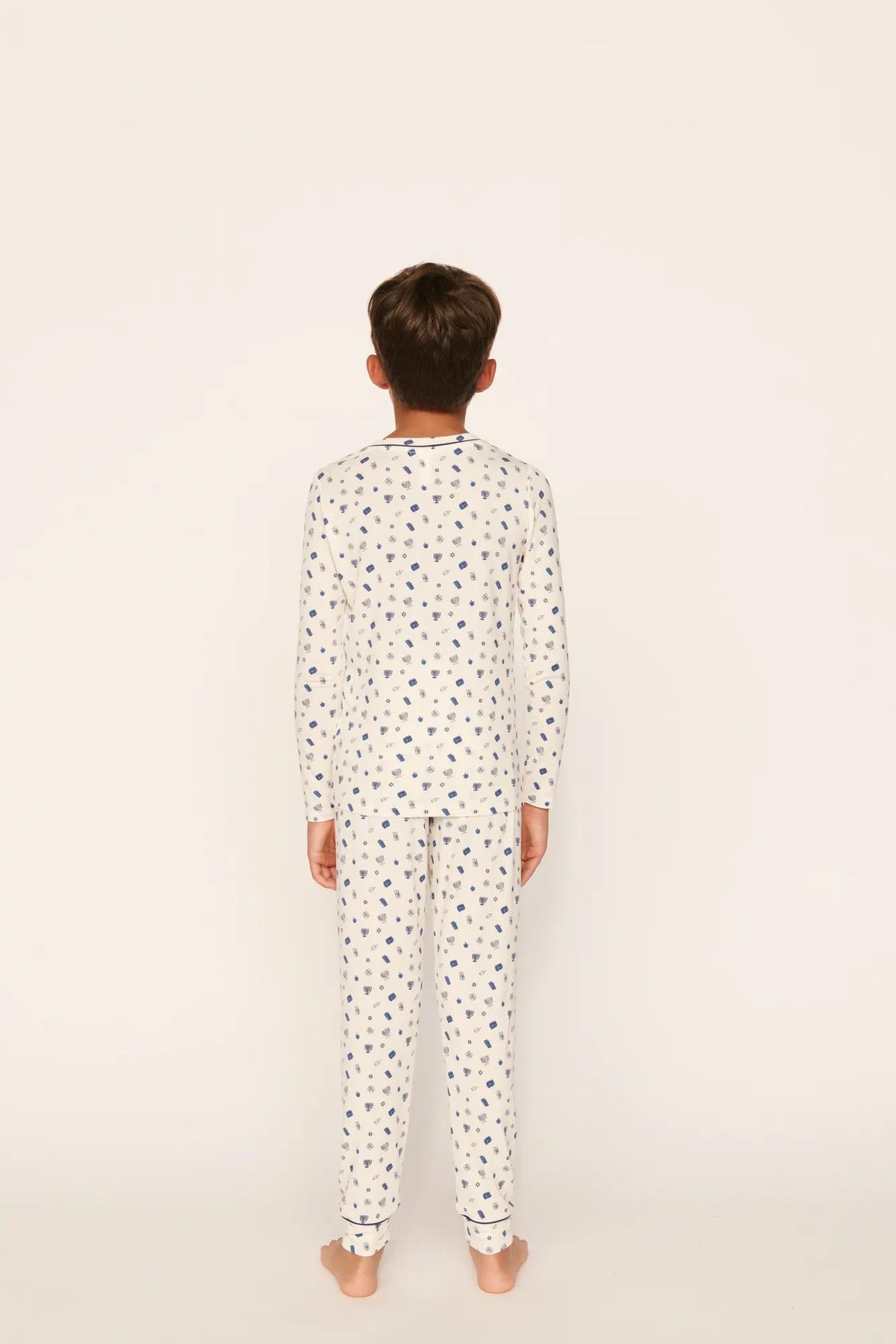 Model is wearing Kids Printed TENCEL™ Modal Unisex Long PJ Set in Twinkling Menorah Ivory/Navy