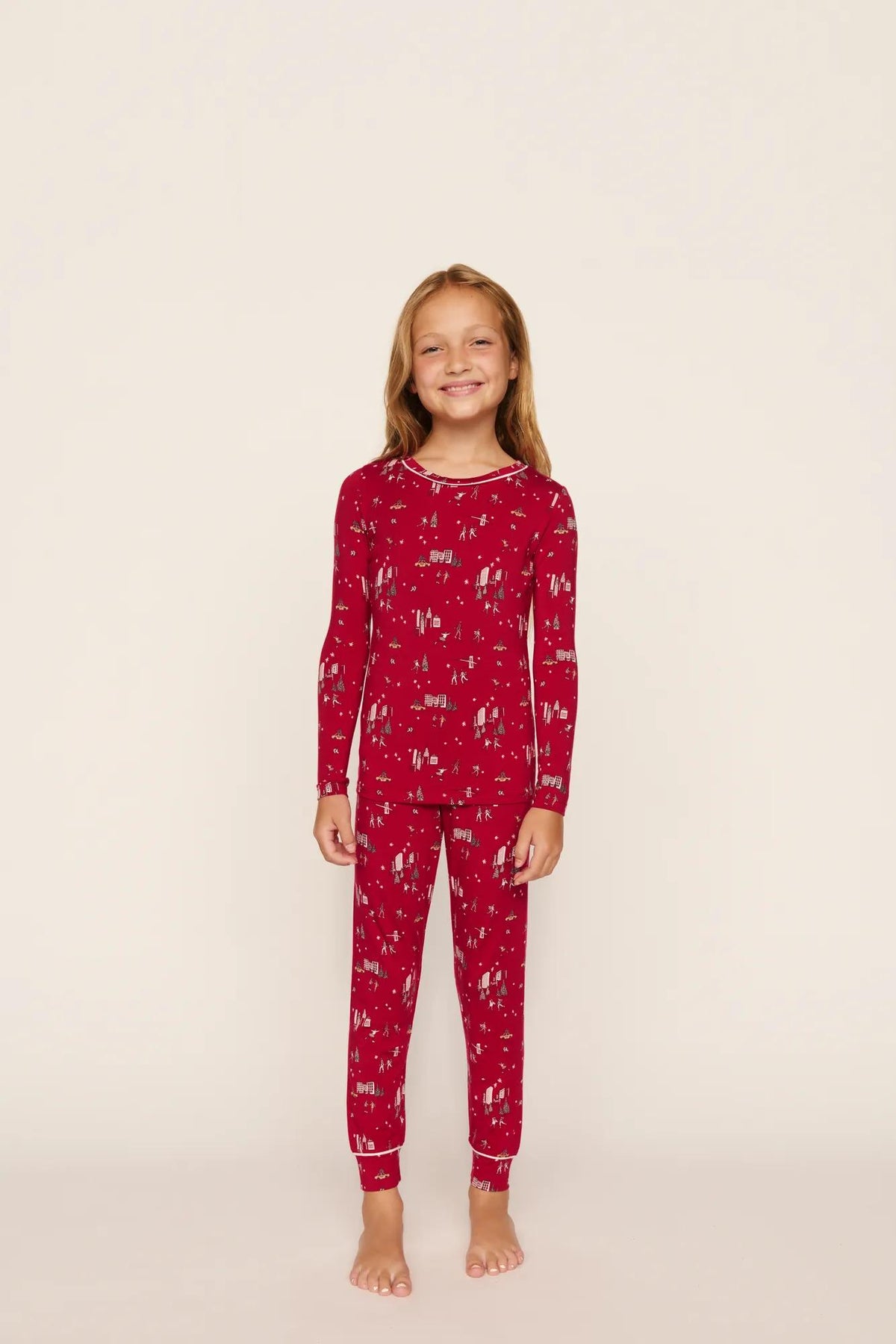 Model is wearing Kids Printed TENCEL™ Modal Unisex Long PJ Set in Winter Skating Holly Red/Ivory