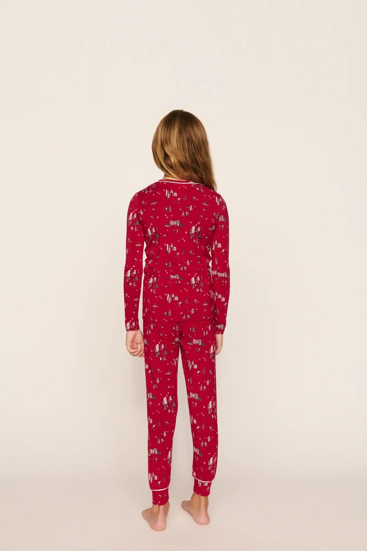 Model is wearing Kids Printed TENCEL™ Modal Unisex Long PJ Set in Winter Skating Holly Red/Ivory