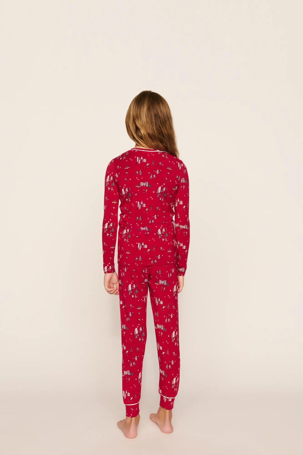 Model is wearing Kids Printed TENCEL™ Modal Unisex Long PJ Set in Winter Skating Holly Red/Ivory