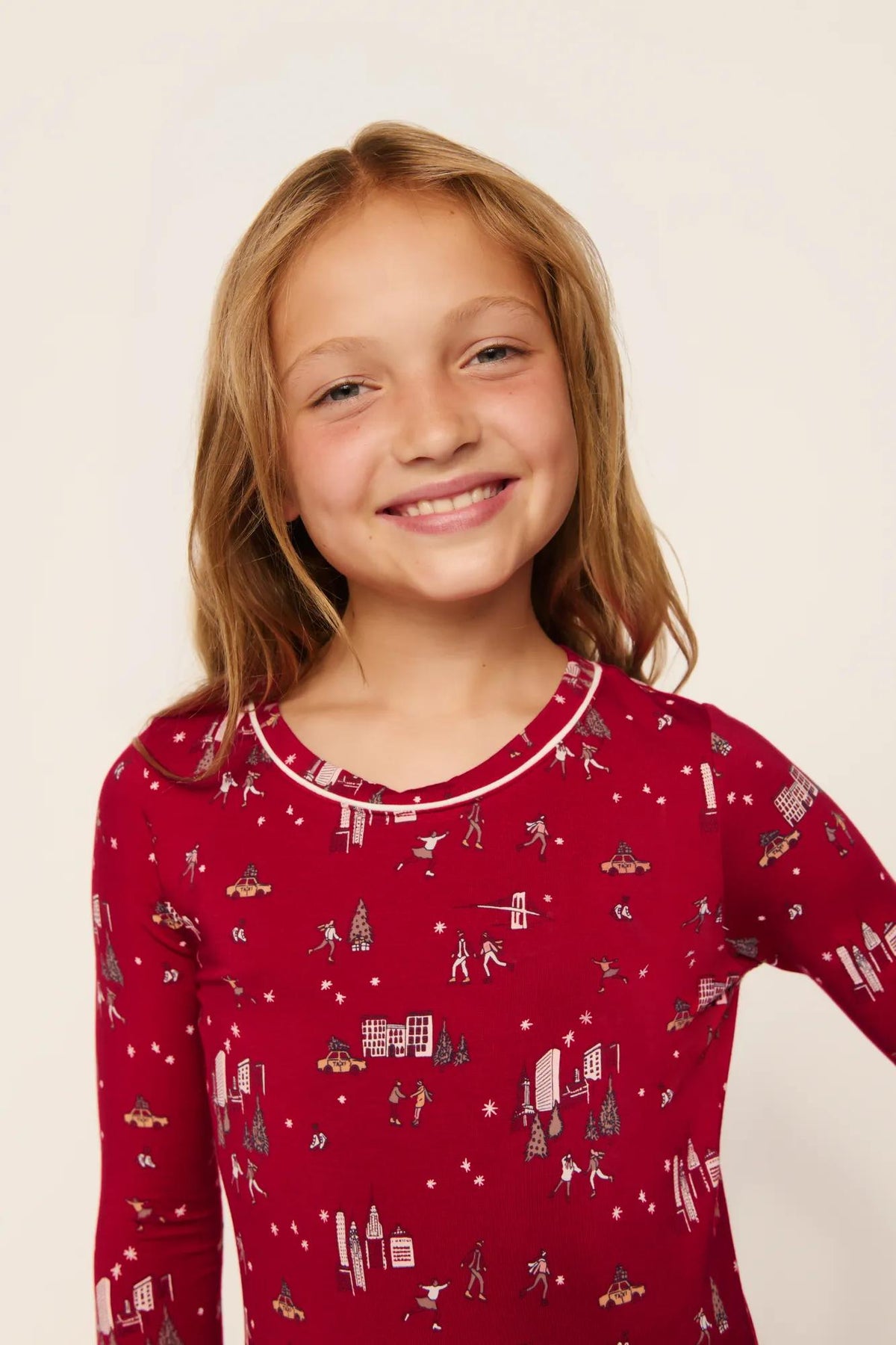 Model is wearing Kids Printed TENCEL™ Modal Unisex Long PJ Set in Winter Skating Holly Red/Ivory